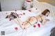 A woman laying on top of a bed covered in red roses.