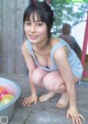 A woman crouching down next to a bowl of colorful balls.