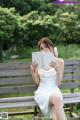 A woman sitting on a bench reading a book.