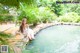 A woman in a white dress sitting on the edge of a pool.