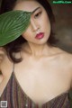 A woman holding a green leaf over her face.