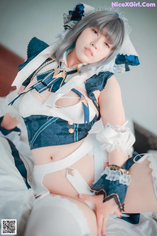 A woman in a maid outfit is sitting on a bed.