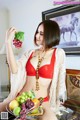 A woman in a red bikini holding a plate of fruit.