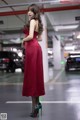 A woman in a red dress standing in a parking garage.