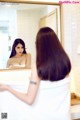 A woman standing in front of a mirror in a bathroom.