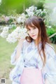 A woman in a kimono holding a bunch of white flowers.