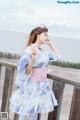 A woman in a blue and white kimono standing on a wooden railing.