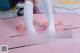 A woman in white stockings is standing on a pink mat.