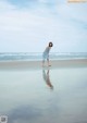 A woman in a blue dress standing on a beach.