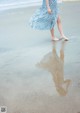 A woman in a blue dress walking on the beach.