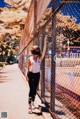 A woman wearing a face mask standing in front of a fence.