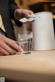 A man in a suit is pouring water into a glass.