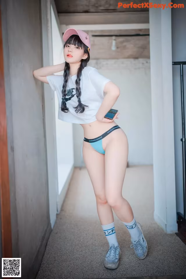 A woman in a white shirt and blue panties posing for a picture.