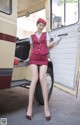 A woman in a red uniform standing next to a bus.