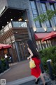 A woman in a red skirt is walking down the street.