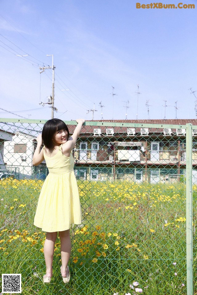 A woman in a yellow dress standing in a field of flowers.