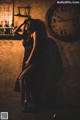 A woman in a red dress leaning against a wall with a clock.