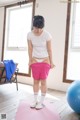 A woman standing on a yoga mat in a room.