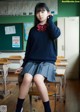 A young woman sitting on a desk in a classroom.