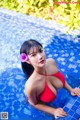 A woman in a red bikini sitting in a pool.