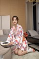 A woman in a kimono sitting on the floor with a laptop.