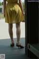 A woman in a yellow dress is standing on a porch.