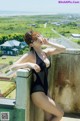 A woman in a black bathing suit leaning against a wall.