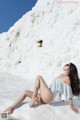 A woman in a bathing suit sitting on a rock.