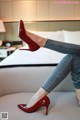 a woman sitting on top of a bed wearing red shoes