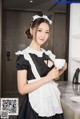 A woman in a maid outfit holding a cup of coffee.