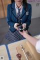 A woman in a school uniform is looking at her cell phone.