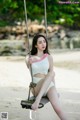 A woman sitting on a swing on a beach.