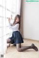 A woman in a school uniform is sitting on the floor.