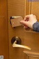 A person opening a door with a card in their hand.