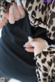 A woman wearing a leopard print coat holding a cell phone.